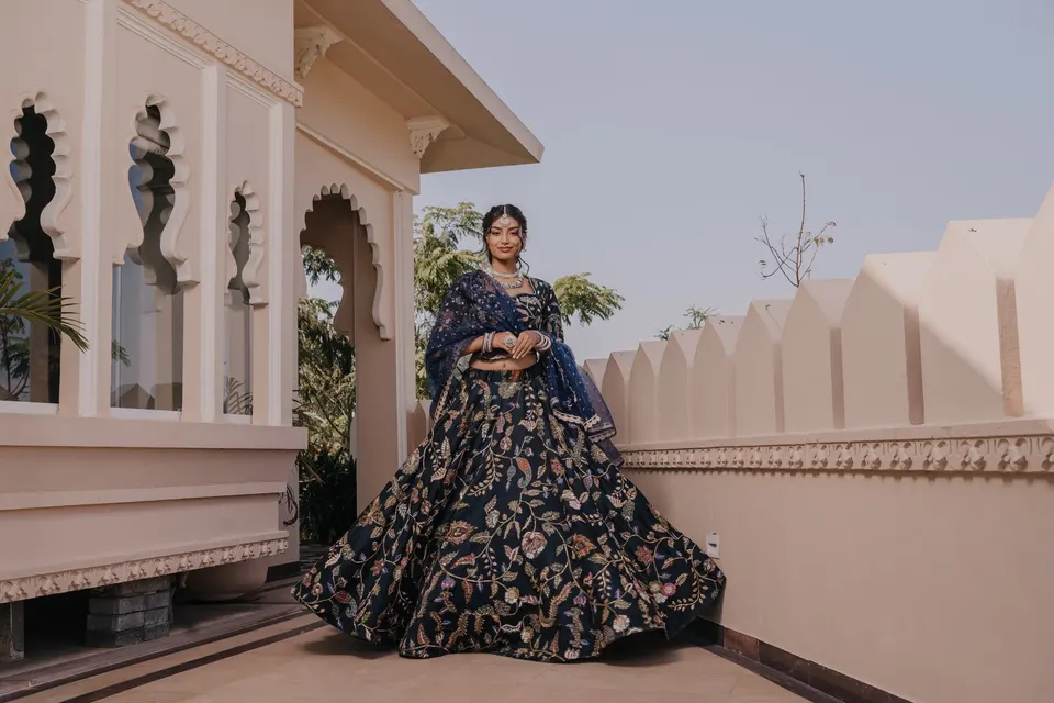 A bride on a terrace in a navy blue lehenga, hand-embroidered in gold and worn with a matching dupatta